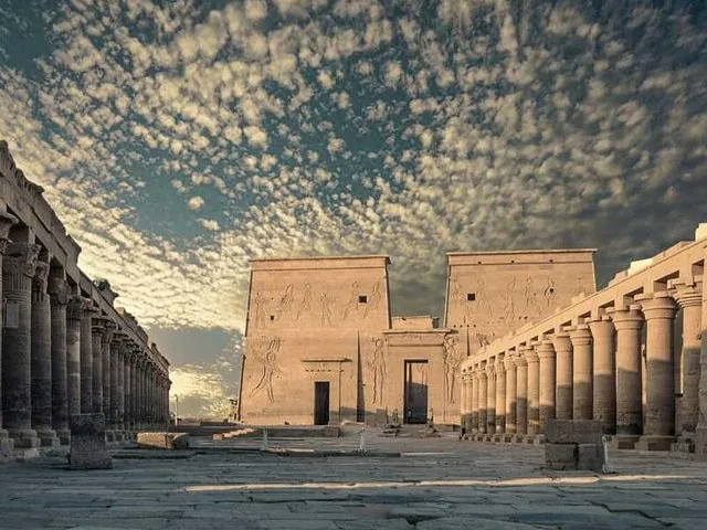 Innenhof mit Säulenreihen, die unter einem dramatisch bewölkten Himmel zum Philae-Tempel führen