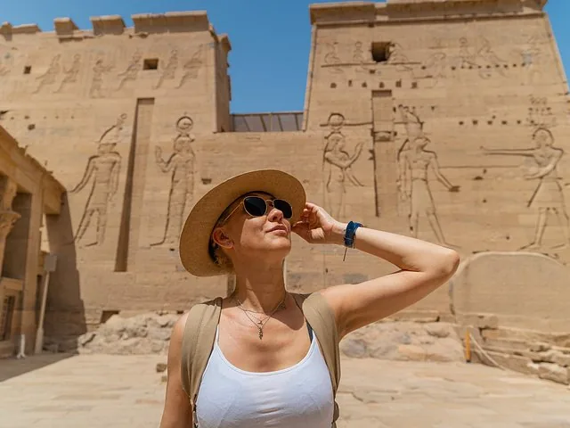 Eine Frau mit Hut und Sonnenbrille posiert vor dem Philae-Tempel.