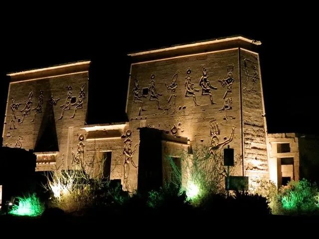 Illuminated Philae Temple at night with carved figures