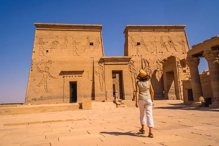 Eine Frau geht auf den Eingang des altägyptischen Philae-Tempels zu.