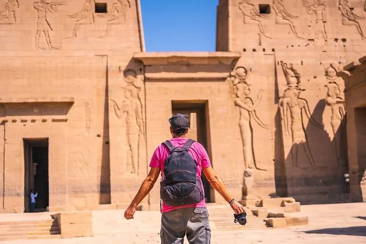 Ein Mann mit Rucksack steht mit Blick auf den altägyptischen Philae-Tempel.