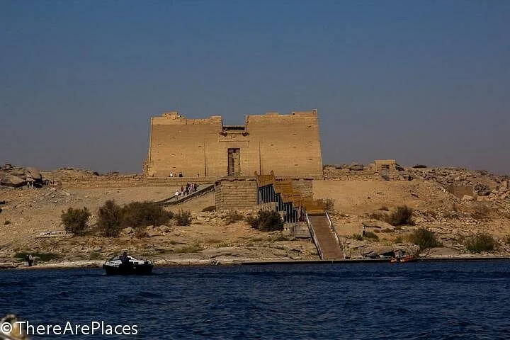 Ansicht aus der Ferne auf den Philae-Tempel auf einer Insel, angefahren mit einem kleinen Boot.