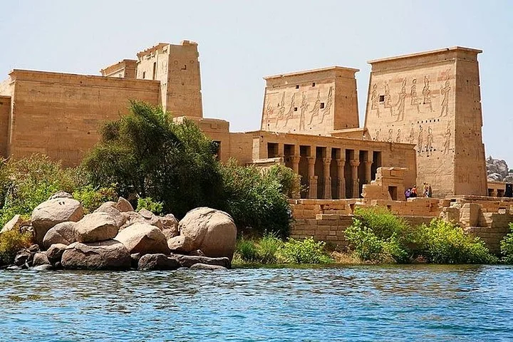 Blick über das Wasser auf den Philae-Tempelkomplex mit großen Felsen im Vordergrund
