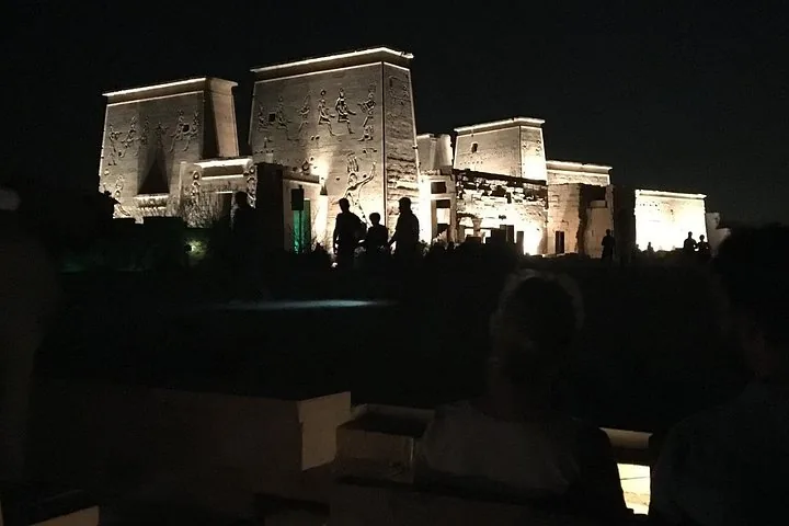 Silhouetted tourists viewing the illuminated Philae Temple at night